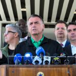 Jair Bolsonaro fala à imprensa em coletiva, com o senador Flávio Bolsonaro ao fundo